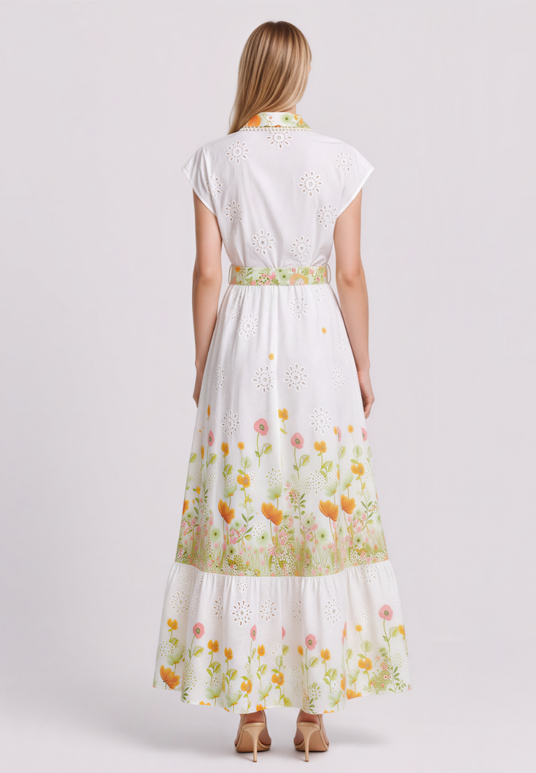 A woman viewed from the back wearing a white eyelet maxi dress with a floral print and a matching waistband, paired with tan high heels, against a light gray studio background.