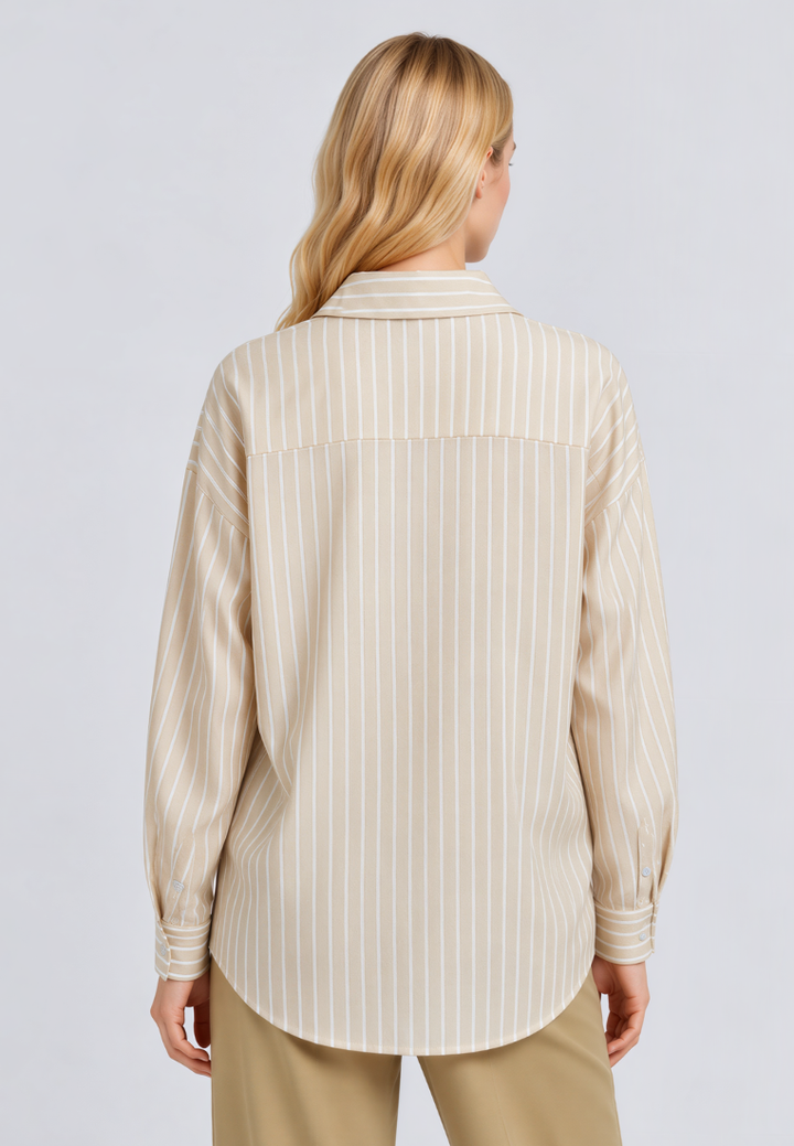 A woman viewed from the back wearing a beige and white vertically striped button-down shirt and khaki pants, set against a plain light gray studio background.